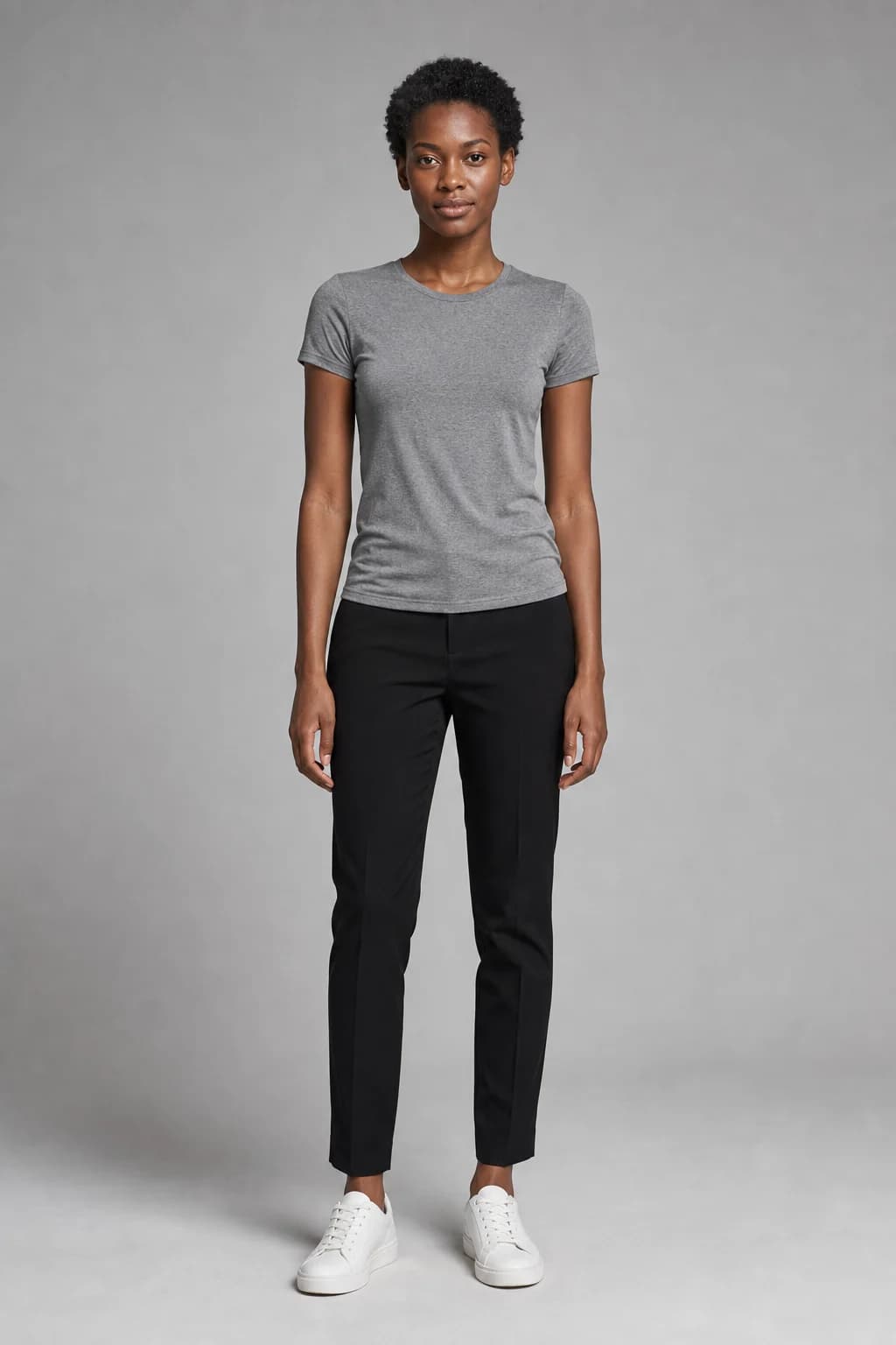 Reference photo of a woman with short natural hair in a grey T-shirt and black trousers against a grey wall