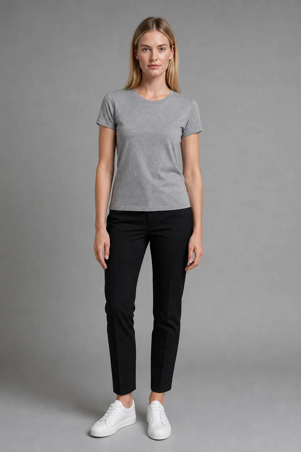 Reference photo of a blonde woman in a grey T-shirt and black trousers against a grey wall